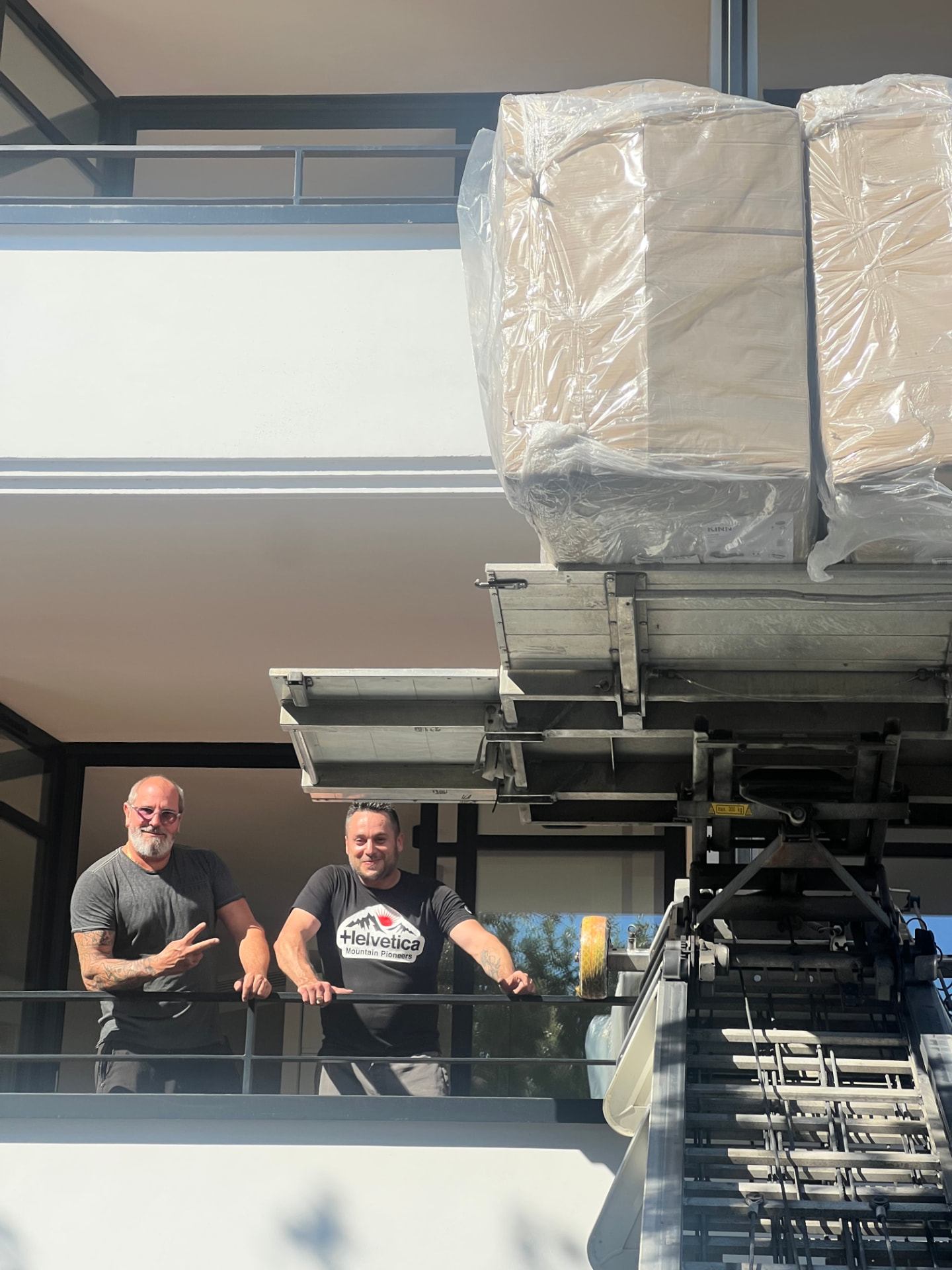 L'équipe GM Service souriant sur un balcon lors d'une livraison par monte-meuble