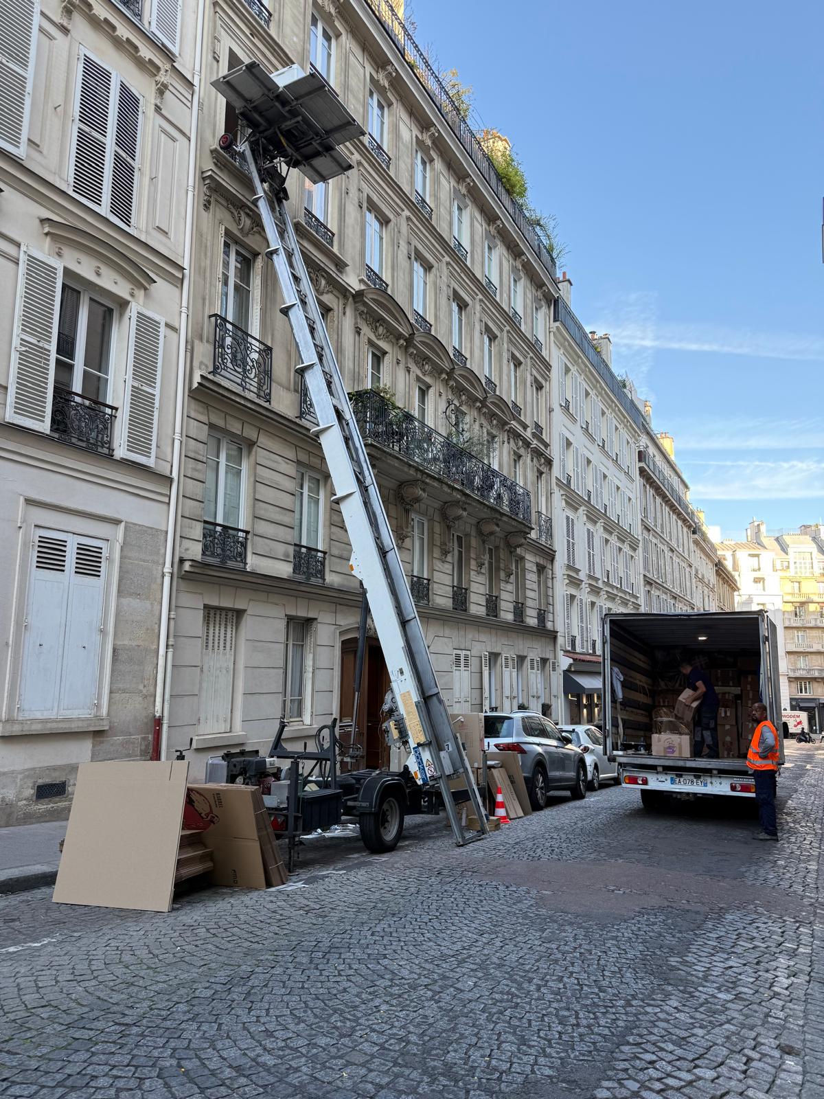 Déménagement avec monte-meuble dans une rue pavée parisienne